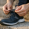 Person bindet sich die Laufschuhe auf einer Treppenstufe