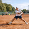Tennisspieler auf einem Sandplatz beim Rueckhandschlag