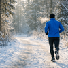 Laeufer auf einem verschneiten Waldweg im Winter