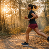 Laeuferin joggt auf einem Waldweg im warmen Herbstlicht